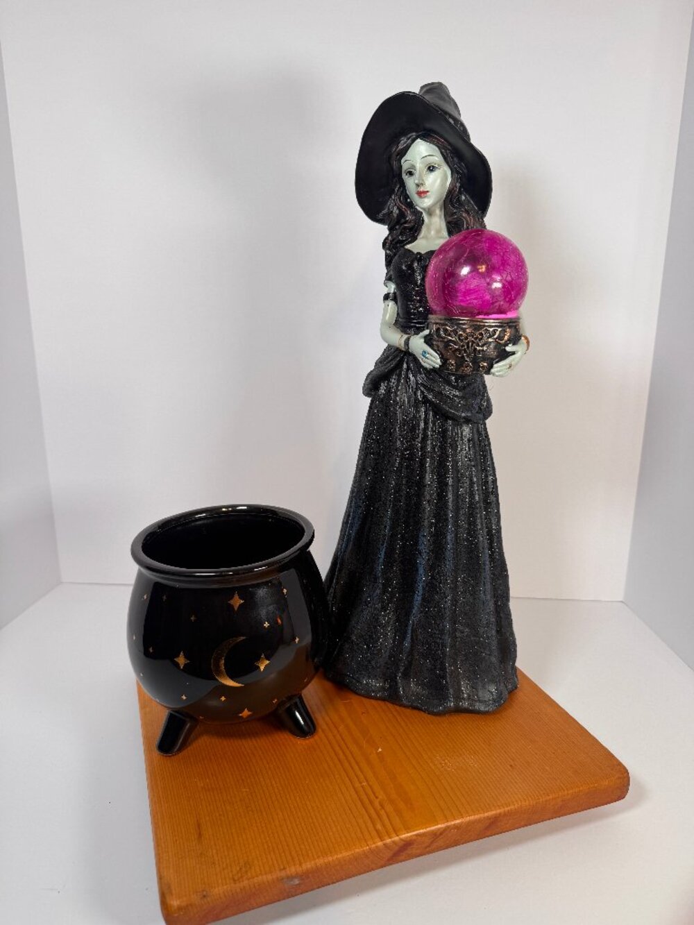 Gothic Witch standing holding a light up pink crystal ball with black cauldron